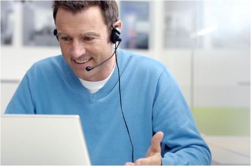 A customer service rep speaks into his headset while using a computer.