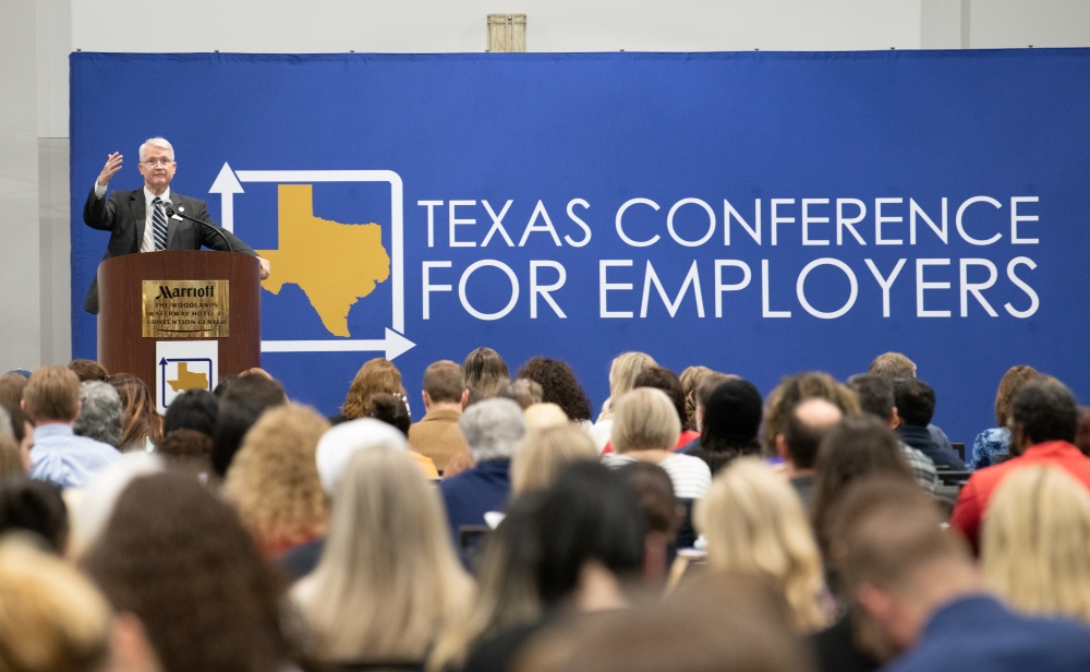A keynote speaker stands at the podium during a Texas Conference for Employers event