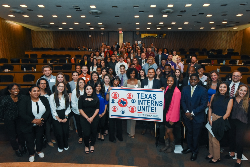 Large group photo of interns, holding a sign that says "Texas Interns Unite!".