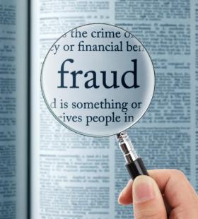 Magnifying glass over the word Fraud