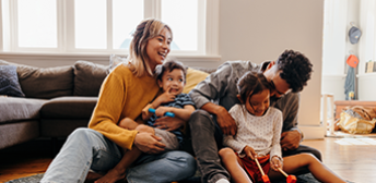 A family laughing while they sit on the floor