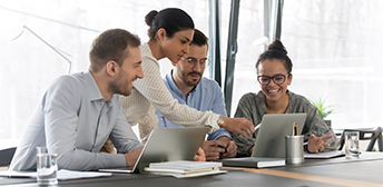 Four employer representatives confer about the user guide they are looking at on a laptop computer.