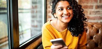 A woman using her phone to search for jobs on MyTXCareer app.