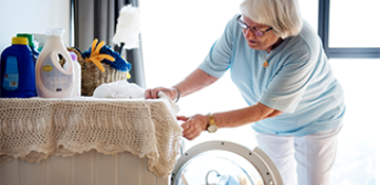 An older woman with glasses doing her laundry.