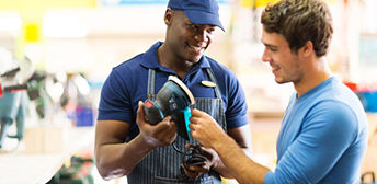 A person showing a person something on a piece o machinery.