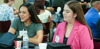 Two attendees at the Texas Intern Network conference discussing with their group.