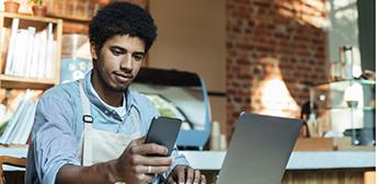 A person using a computer and a cell phone.
