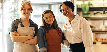 A group of women, one with down syndrome, posing in uniform at storefront