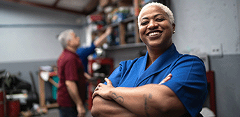 A woman smiling at the camera with her arms crossed.
