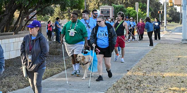 Students from Criss Cole Rehabilitation Center walking to the event with their white canes and service dogs