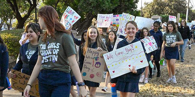 A group of girls from The Girls School of Austin with festive banners and posters celebrating 2024 White Cane Day.