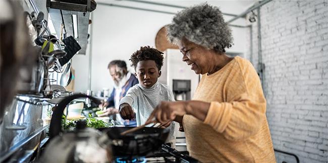 A grandmother and her grandson cooking in the kitchen.