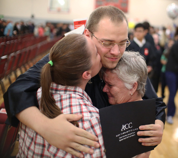 Three family members hugging at a graduation ceremony