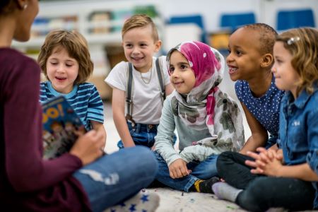 Child gather around their teacher for story time