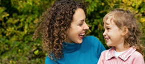 A mom smiles and looks at her smiling child.